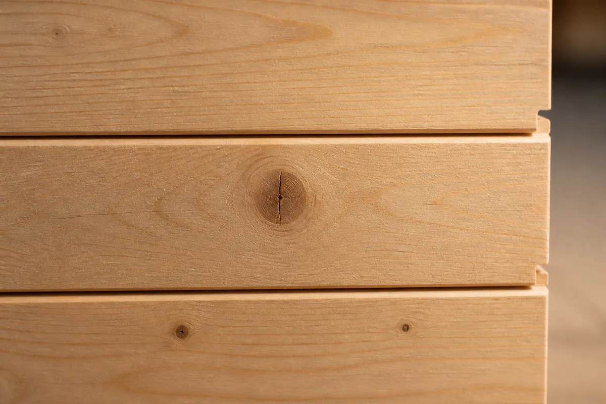 Mur de salon habillé de lambris en bois clair à lames verticales